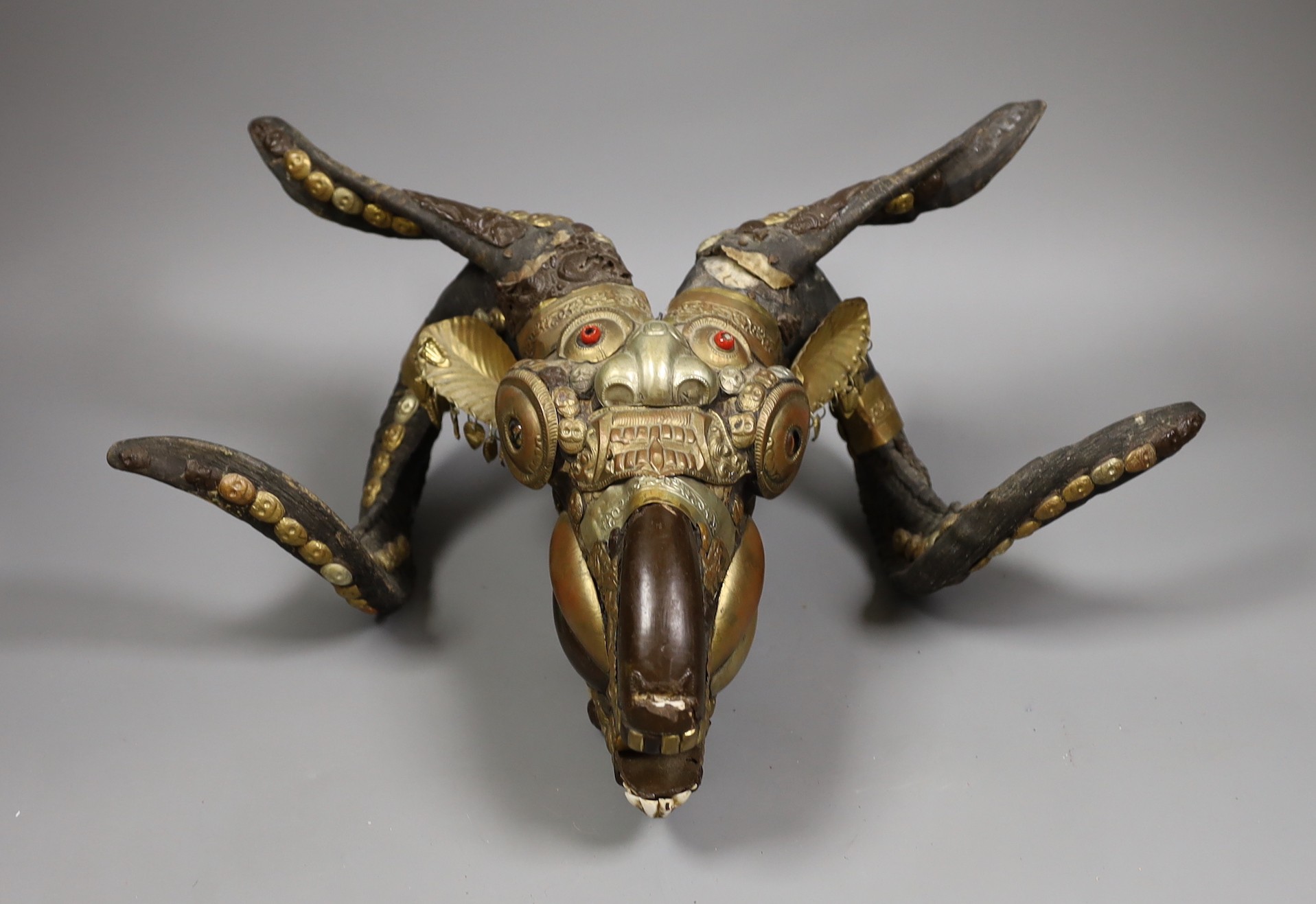 A Buddhist decorated ram's skull with brass decor, 20cm tall